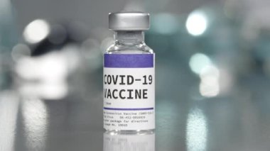Covid-19 Coronavirus aşı şişesi tıbbi laboratuvarda yavaşça dönüyor..