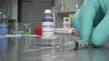Aşı ve antikor şişesi tıp laboratuarında yanında şırıngayla makro görüş için yakınlaşıyor..