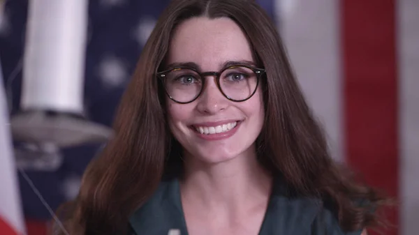 Amerikan Bayrağı önünde gülümseyen genç bir kadın.