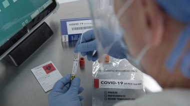Laboratuvarda kovid 19 kiti üzerinde çalışan tıbbi personelin omzunun üstünden örnek alıp test tüpüne koymaları..