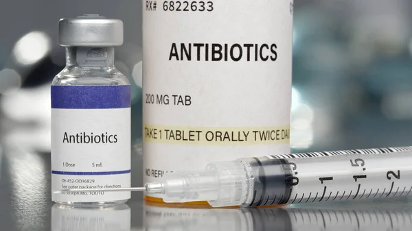 Antibiotics in vial and pill bottle in medical lab with syringe