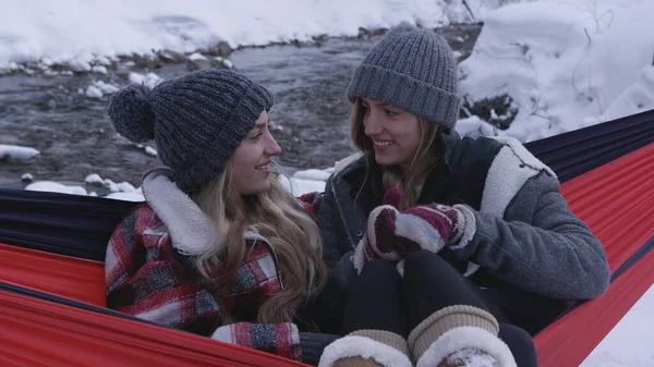 Kışın birlikte hamakta oturan kadınlar için kar kanyondan nehri kaplıyor..