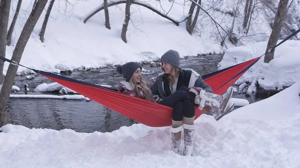 Dışarıda karda hamakta oturan ikiz kardeşler yan yana rahatça otururken konuşuyorlar..