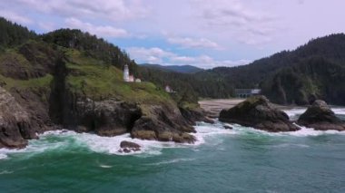 Oregon kıyısındaki Heceta Baş Feneri 'nin havadan görünüşü okyanusun üzerinden geriye doğru uçuyor..