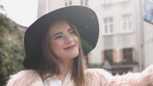 Lachende vrouw zelf fotograferen in stedelijke straat. Mooie Kaukasische brunette meisje in witte jas met maakt selfie. Een toerist. — Stockvideo