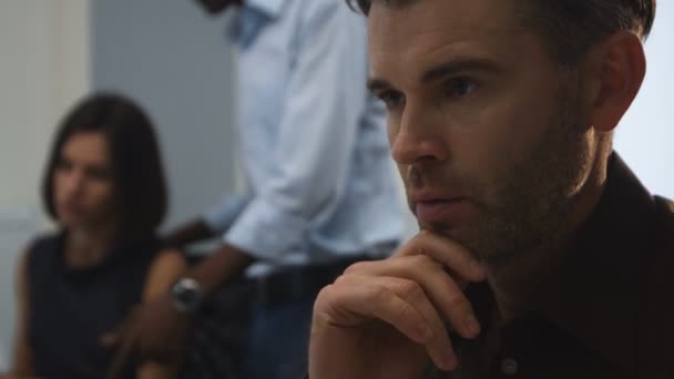 Handsome serious man working in an his office, while his colleagues discussing new project. — Stock Video