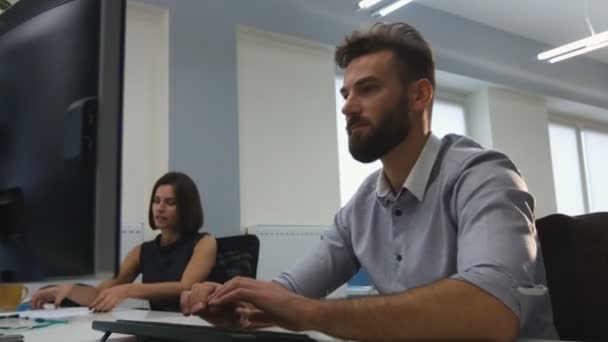 Büroangestellte mit Laptop, während seine Kollegen Dokumente prüfen. — Stockvideo