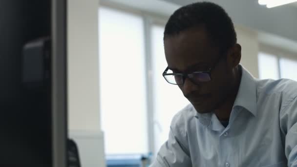 Joven oficinista con gafas usando su portátil en la oficina . — Vídeos de Stock