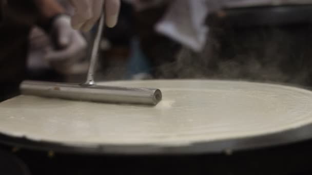 Hand met speciaal gereedschap koken pannenkoeken op de plaat... de actie in Real Time. — Stockvideo