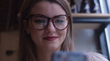 Kafede kahve içme telefon üzerinde app gülümseyen kullanan akıllı kız. Güzel çok kültürlü genç casual kadın profesyonel üstünde hareket eden telefon.