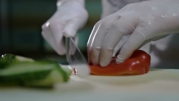 Close-up van chef-kok hakken van een wortel met rode peper op snijplank. — Stockvideo