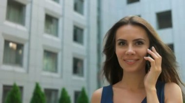 Smartphone banliyö şehir, kullanan çekici kadın oldukça karmaşık bir Modern ofis binaları karşı telefonla konuşurken genç iş kadını