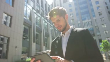 Genç adam bir iş merkezi önünde onun tablet kullanma.