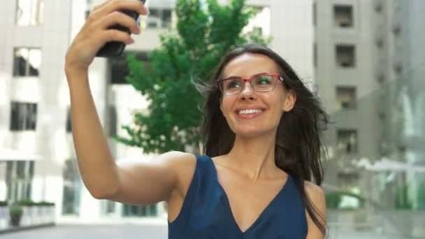 Jovem senhora tirando selfies na frente de um centro de negócios . — Vídeo de Stock