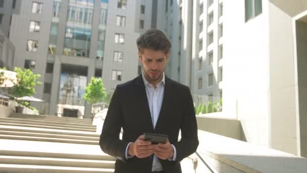 Junger Mann mit Tablet vor einem Business Center. — Stockvideo