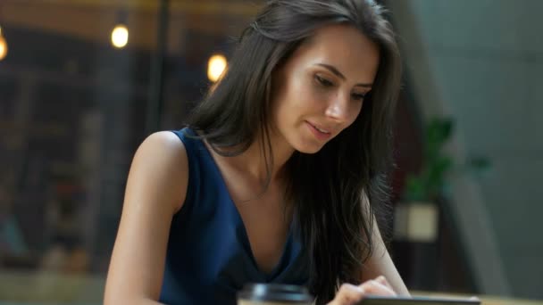 Trabajando en el café. Joven hermosa mujer de pelo largo sentado en la mesa y el uso de la tableta en la cafetería al aire libre — Vídeos de Stock