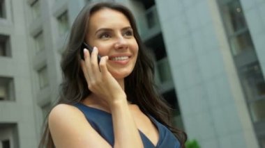 Smartphone banliyö şehir, kullanan çekici kadın oldukça karmaşık bir Modern ofis binaları karşı telefonla konuşurken genç iş kadını