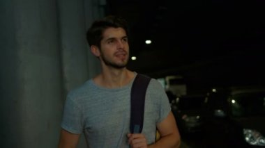 Karanlık bir sokakta yürüyen genç adam.