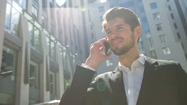 Giovane uomo d'affari pensieroso che parla al telefono all'aperto — Video Stock