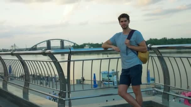 Jonge knappe man poseren op een camera voor een rivier. — Stockvideo