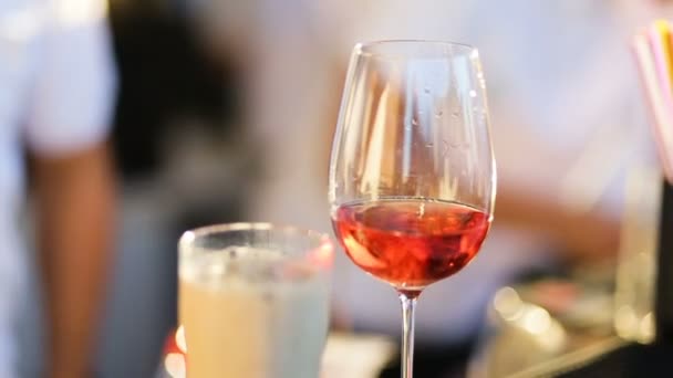 Mains barman versé champagne dans deux verres avec des verres à vin rouge cocktail sur les jambes hautes, verre transparent, bouteille de champagne sombre, cocktails avec de la glace, mousse se lève et tombe rapidement, jour d'été — Video