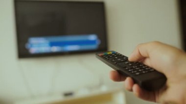 Büyük Tv programı. Uzaktan kumanda tutarak ve evde kanepede otururken Tv izlerken neşeli yakışıklı genç