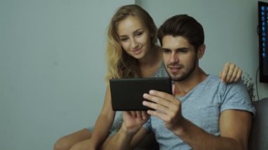 Mutlu genç çift bir tuğla duvar arka plan moda forması giymiş bir tablet kullanma