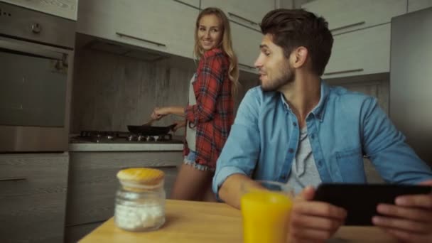 Casal jovem preparando café da manhã e usando tablet . — Vídeo de Stock