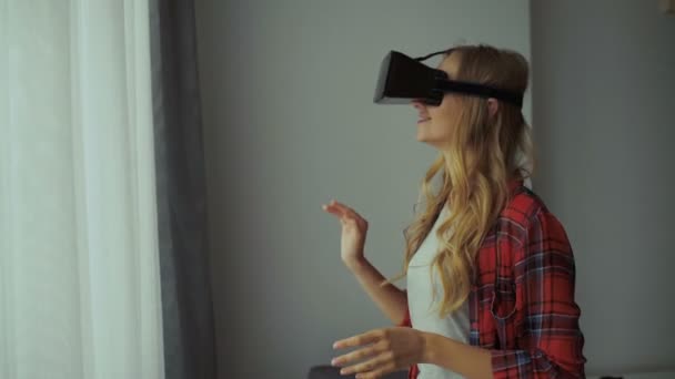 Woman in VR headset looking up at the objects in virtual reality. VR is a computer technology that simulates a physical presence and allows the user to interact with environment. — Stock Video