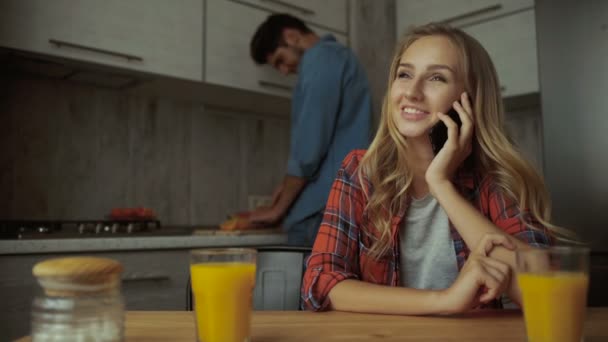 Vrouw praten over telefoon, terwijl de man bereiden van voedsel. — Stockvideo