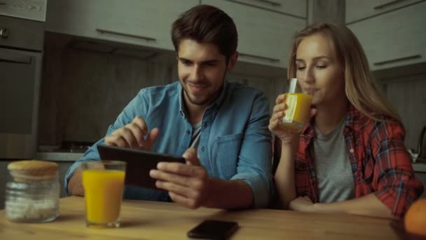 Par använder en digital surfplatta medan du äter frukost hemma. — Stockvideo