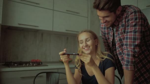Happy couple photographing jus and oranges in the kitchen. — Stockvideo