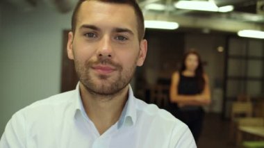 Kameraya bakarak mutlu gülümseyerek çarpı işareti, yakışıklı kendine güvenen genç işadamı duran kolları portresi.