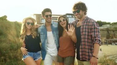 Bir grup arkadaşıyla kumsalda eğleniyor kadeh