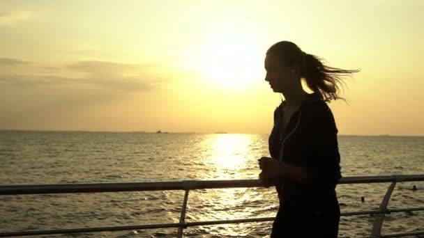 Mooie brunette luisteren naar muziek, uitgevoerd in de buurt van de zee. — Stockvideo