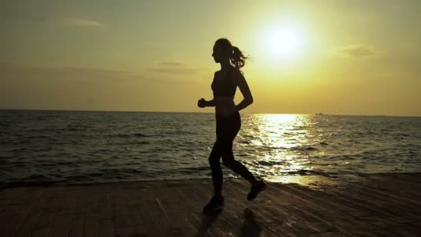 Attractive young sexy lady listening to music and running in the evening time. — Stockvideo