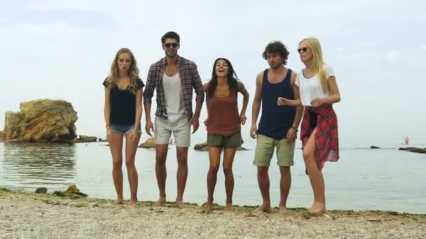 Rückansicht einer Gruppe von Freunden, die am Strand in die Luft springen — Stockvideo