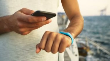 Beyaz t-shirt kontrol mil onun fitness İzleyicisi'ni giyen adamın yakın çekim