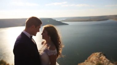 Çok güzel muhteşem mutlu gelin ve güneşli çarpıcı Dağları arka plan üzerinde sarılma şık damat.