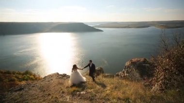 Genç yakışıklı damat takım elbise ve beyaz zarif elbise daimi bir dağ Gölü kıyısında gelin.