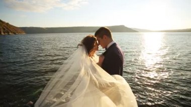 Ellerinin üstünde güneş ışığı onun güzel genç gelin taşıyan ve gülümseyen, dağın kalırken şık mutlu damat.