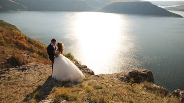 Marido guapo sosteniendo a su novia feliz en el pintoresco lugar en la montaña . — Vídeo de stock
