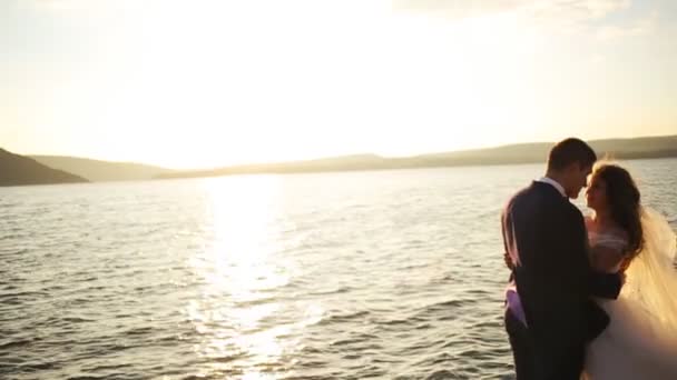 Силуэт любящей счастливой пары, обнимающейся на фоне заходящего солнца  . — стоковое видео
