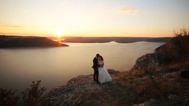 Jolie mariée heureuse et aimante embrassant avec son élégant grand mari, tout en posant sur la montagne . — Video