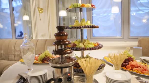 Вкусный шоколадный фонтан и много сладких десертов, приготовленных в хорошем ресторане для свадебной вечеринки . — стоковое видео