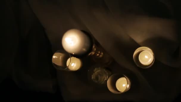 Combattez les bougies de mariage brûlant la nuit. Gros plan de la lumière dorée de flamme de bougie et petite rose blanche sur fond sombre 