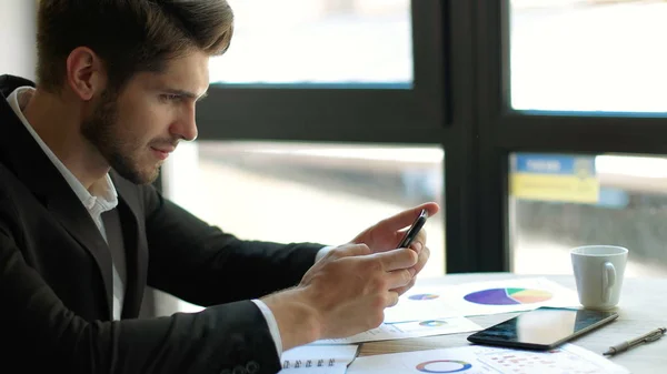 Beklenen ileti. Onun çalışma evinde otururken gülümseme ile onun akıllı telefon kullanan genç yakışıklı adam
