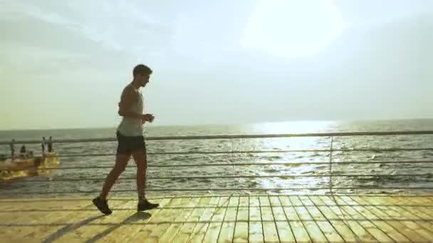 Jovem bonito homem ativo correndo e levando um tempo para relaxar depois de longa distância de corrida . — Vídeo de Stock