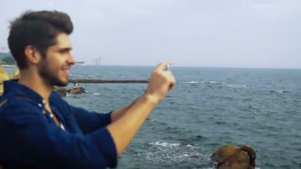 Jeune photographe souriant prenant de belles photos de la mer profonde bleue . — Video