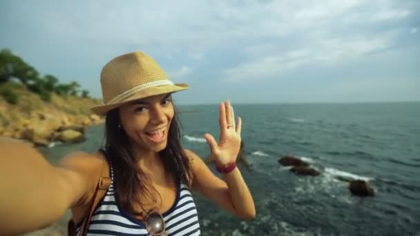Attraktive junge glückliche Touristin, die Fotos von sich und der Tiefsee macht, während sie auf dem Stein steht. — Stockvideo